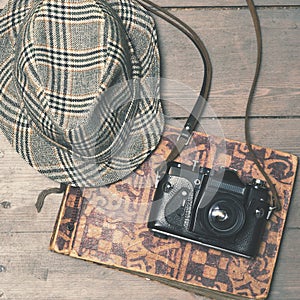 Retro camera with vintage trilby hat and photo album on wooden b