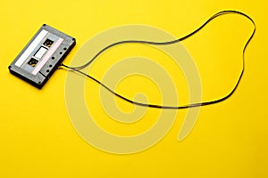 Retro cassette with tape over yellow table background. top view. copy space