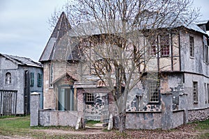 Retro catholic church with an open front door and a cross over the entrance. Yard with trees and gates of the old European church