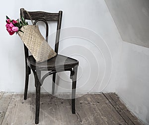 Retro chair in empty room with straw bag and flowers