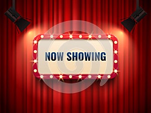 Retro cinema or theater frame illuminated by spotlight. Now showing sign on red curtain backdrop. Movie premiere signs