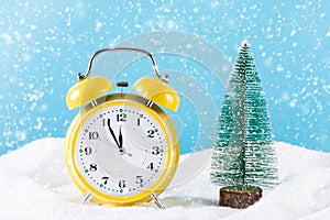 Retro clock and Christmas fir tree on snow and it`s snowing winter day