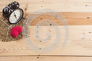 Retro clock with love heart yarn on wood background