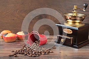 Retro coffee grinder, coffee mill coffee cup, chocolate cupcake, muffins, coffee beans. Wood backg