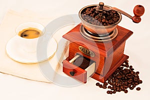 Retro coffee mill and cup of coffee on white background