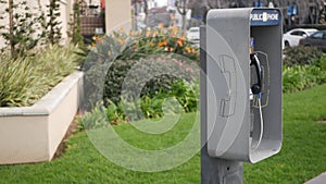 Retro coin-operated payphone station for emergency call on street, California USA. Public analog pay phone booth. Outdated