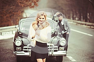 Retro collection car and auto repair by mechanic driver. Bearded man and sexy woman in fur coat. Couple in love on