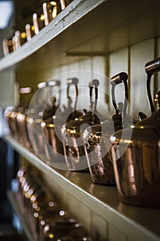 Retro copper kettles presented on a kitchen shelf