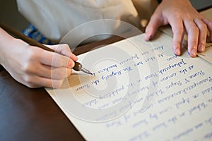 Retro effect faded and toned image of a girl writing a note with a fountain pen antique handwritten letter.