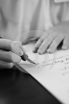 Retro effect faded and toned image of a girl writing a note with a fountain pen antique handwritten letter.