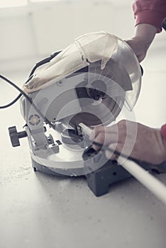 Retro effect faded and toned image of a workman using an electric circular saw