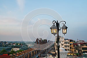 Retro electrical lamp with Long Bien metal railway bridge on background in Hanoi, Vietnam