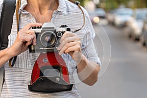 Retro film photo camera with a leather case in female hands on the city street