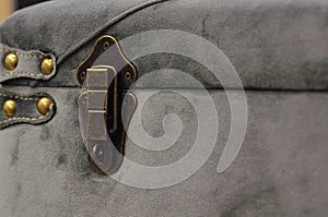 Retro furniture fittings, an aged steel lock on a soft pouffe upholstered in fabric. The corner of the pouffe is