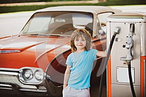 Retro gas station. Smiling Kid boy at the gas station. Waiting for fuel. Kid fueling vintage car at gas station. Refuel