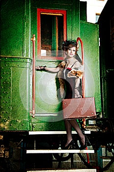 Retro girl with suitcase near the old train.