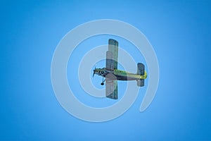 Retro green biplane plane in the blue sky