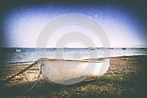 Retro image of a boat on a shingle beach.
