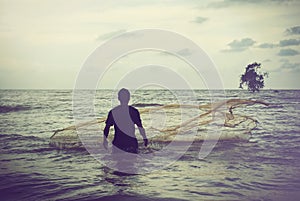 Retro image concept fisherman throwing his fishing net during sunset