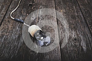 Retro incandescent lamp with damaged wires, on wooden background with space for text. Concept - neglect of fire safety