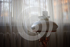Retro lamp on the background of a window with a battery and tulle