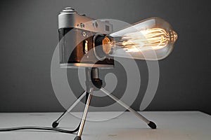 Retro lamp from an old camera with an Edison lamp on a gray background. Concept is a good idea