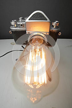 Retro lamp from an old camera with an Edison lamp on a gray background. Concept is a good idea