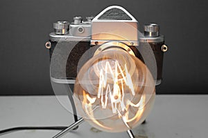 Retro lamp from an old camera with an Edison lamp on a gray background. Concept is a good idea