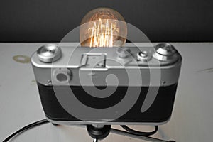 Retro lamp from an old camera with an Edison lamp on a gray background. Concept is a good idea