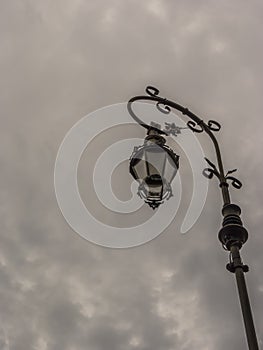 A retro lampost at a dark sky with clouds