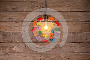 Retro light bulb and group of jigsaws on wooden background - idea, innovation, teamwork and leadership concept. Space for text