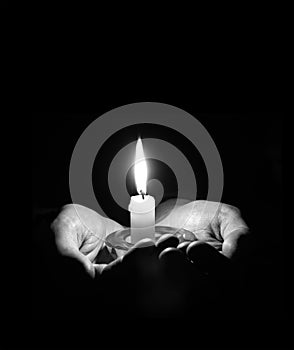 Hands holding a burning candle in dark room