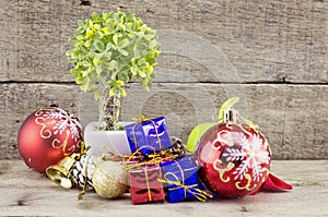 Retro look Christmas decorations with red ball,green ball,red ribbon,bell,samll tree on white pot, and artificial flower. aged and