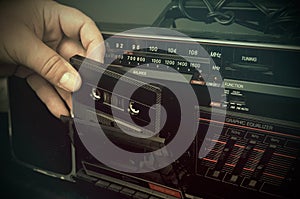 Retro Looking Photo of a Man Inserting a Cassette in an Old Dusty Cassette Player