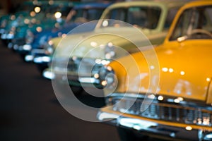 Retro luxury cars stand in a row, blurred background texture, bokeh. The lights of a sun.