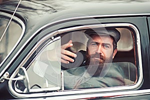 Retro man in retro car showing communicative gesture.