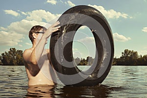 Retro man in summer lake have fun with inner tube