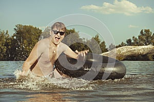 Retro man in summer lake have fun with inner tube