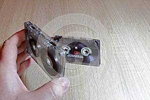 Retro medium for recording and playing music. Hand holding an old audio cassette.