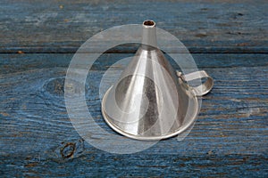 Retro metal funnel with handle on old wooden background