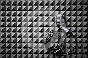 Retro microphone with cable lying on acoustic foam panel background