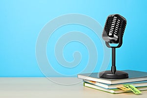 Retro microphone and notebooks on table against light blue background, space for text. Job interview
