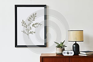 Retro modern compositon of living room interior with design teak commode, black mock up poster frame, clock, plant, decoration.