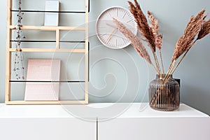 Retro modern decoration wall in the living room with pastel colors, white clock and shelf, modern vase with pampas grass