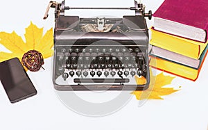 Retro and modern writer gadgets: mobile phone, old typewriter, stack of books and yellow dry leaves