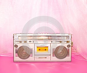 Retro music concept with silver cassette player against pink and purple background