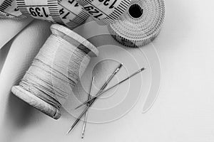 Retro needle and thread lie on the fabric. Tools for a tailor or seamstress. Black and white photography