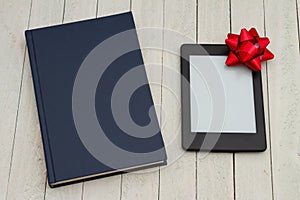 Retro old blue book on a desk with an ereader with gift bow photo