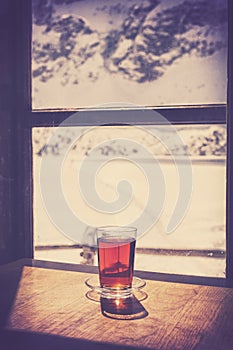 Retro old film style glass of hot tea on wooden table.