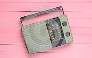 Retro old radio receiver on a pink wooden background. Top view. Outdated technology.